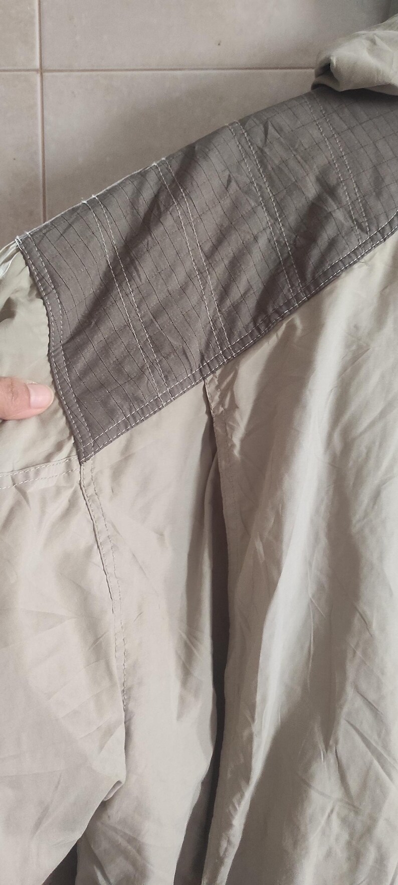 May include: A beige jacket with a brown patch on the shoulder. The patch has a textured design.