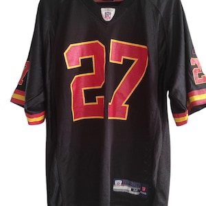 Pode incluir: Camisola de futebol preta com guarnições vermelhas e amarelas. O número 27 está impresso na frente em vermelho e amarelo. O logotipo da NFL é visível na frente da camisola.