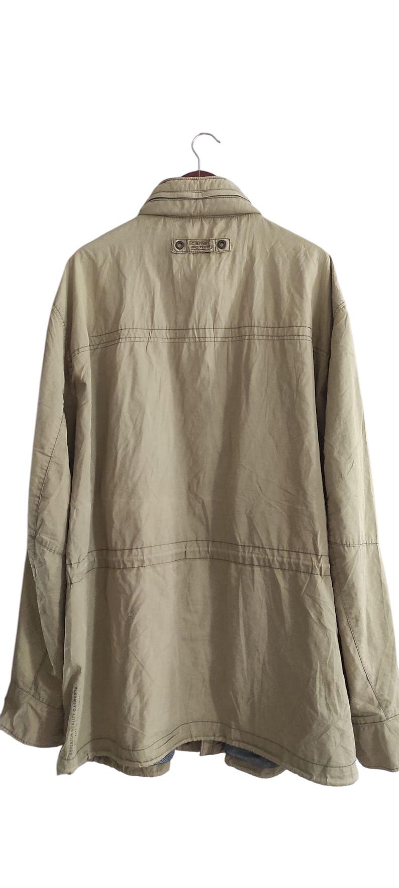 May include: A beige jacket with a brown label on the back that says "The North Face" and a zipper closure.