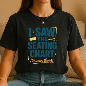 Puede incluir: Camiseta negra con el texto "I SAW THE SEATING CHART I've seen things..." en azul y amarillo. La camiseta tiene cuello redondo y mangas cortas. El texto está en una fuente divertida.