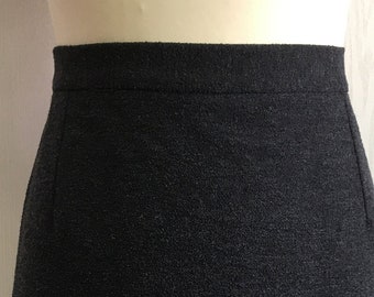 May include: A dark gray pencil skirt with a straight silhouette. The skirt has a zipper closure and a smooth, textured fabric.