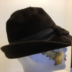 Puede incluir: Un sombrero fedora de fieltro marr&oacute;n con ala ancha y una cinta negra alrededor de la corona.