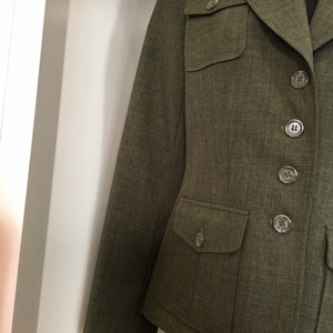 Op de afbeelding: Een groene blazer met knoopsluiting en twee grote klepzakken.