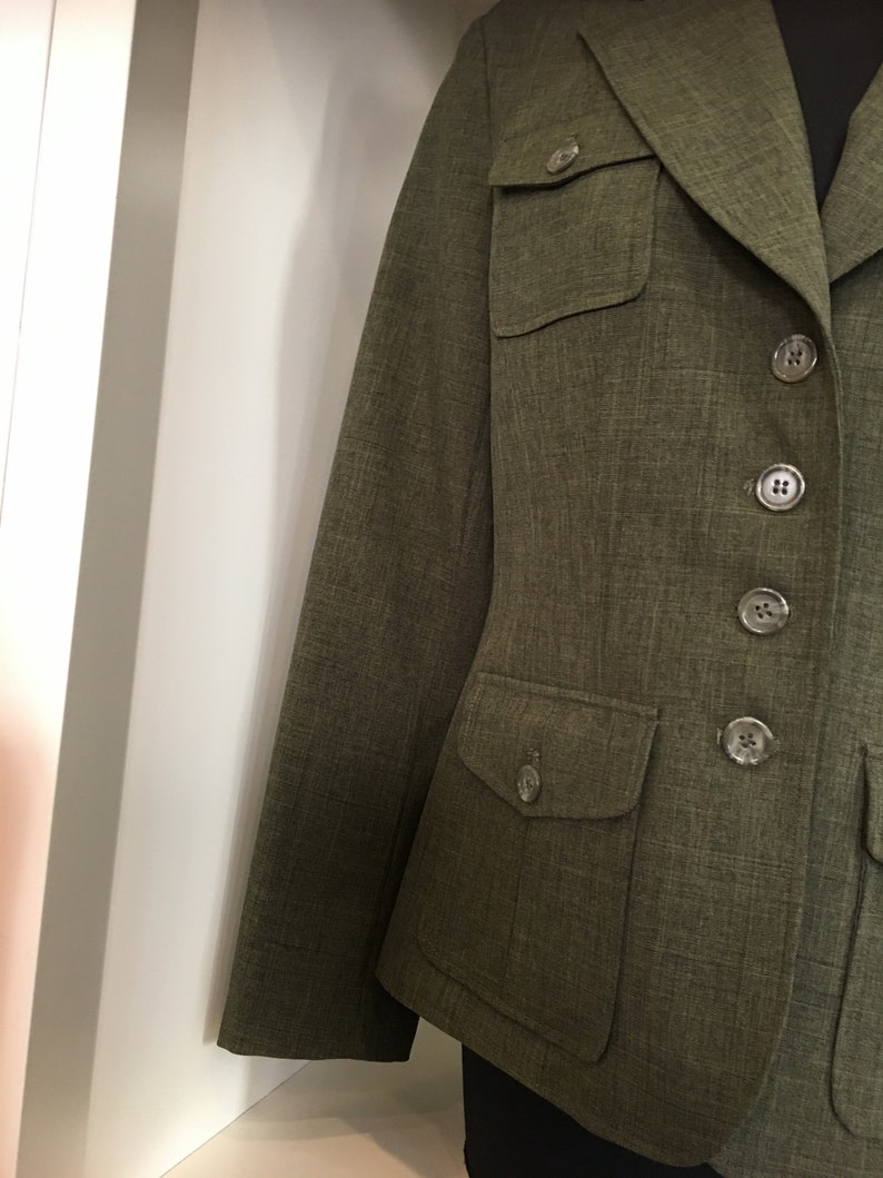 Op de afbeelding: Een groene blazer met knoopsluiting en twee grote klepzakken.