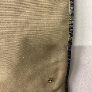 May include: A beige canvas tote bag with a gold G logo and a blue and green patterned trim.