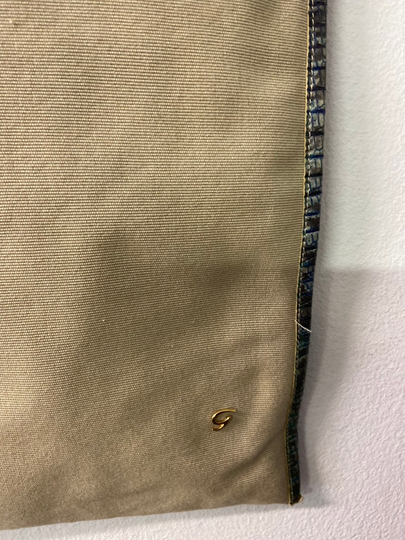 May include: A beige canvas tote bag with a gold G logo and a blue and green patterned trim.