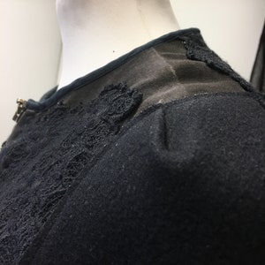 Puede incluir: Detalle de encaje negro en un su&eacute;ter negro. El encaje es un delicado patr&oacute;n floral.