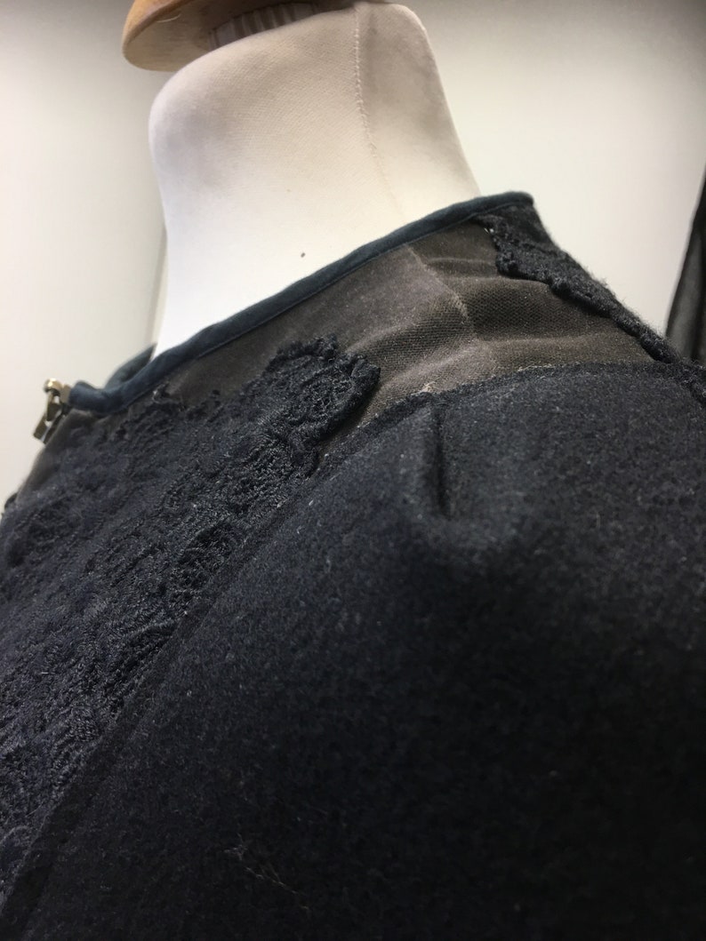 Puede incluir: Detalle de encaje negro en un su&eacute;ter negro. El encaje es un delicado patr&oacute;n floral.