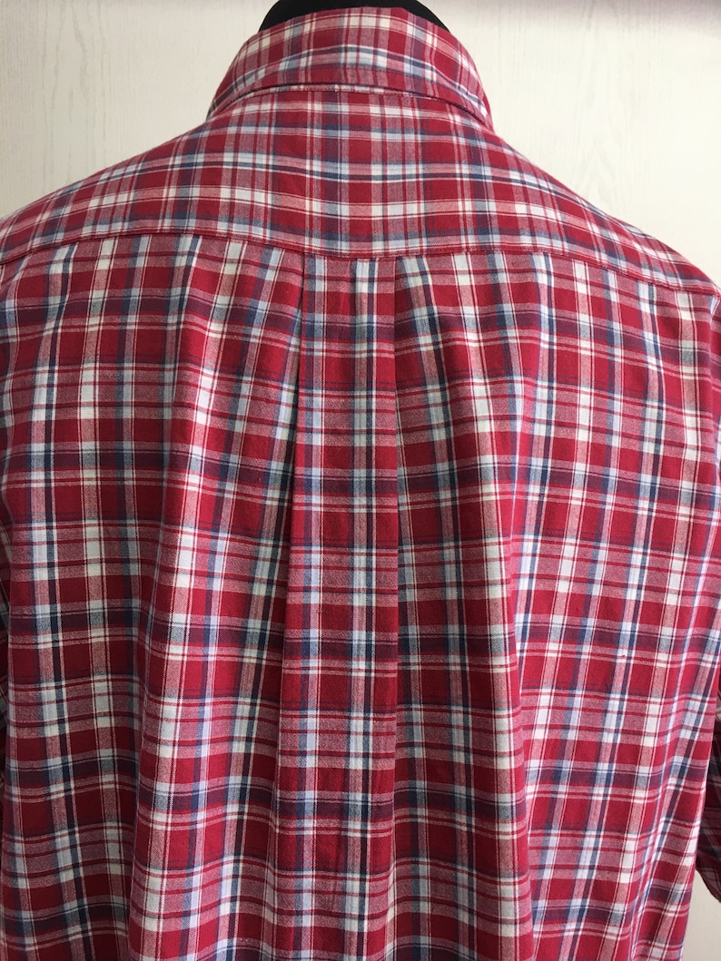 Puede incluir: Camisa de botones a cuadros rojos, blancos y azules. La camisa tiene un corte cl&aacute;sico y un cuello.