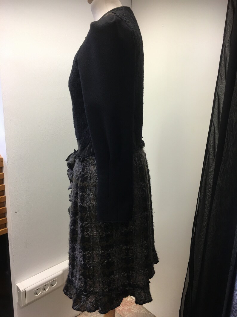 Puede incluir: Un vestido negro con falda con volantes y mangas largas. La falda est&aacute; hecha de una tela texturizada con un patr&oacute;n negro y gris.