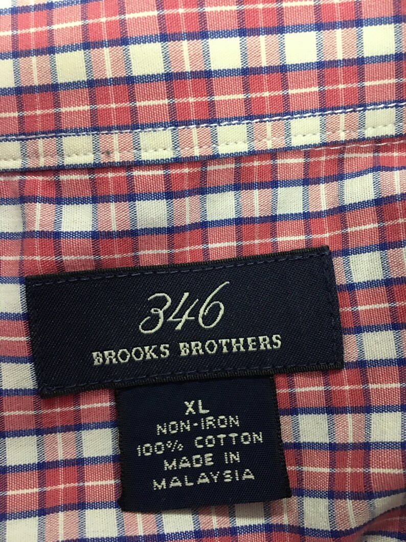Pu&ograve; includere: Un'etichetta blu e bianca con il testo "346 Brooks Brothers" e un'etichetta bianca pi&ugrave; piccola con il testo "XL Non-Iron 100% Cotone Prodotto in Malesia".