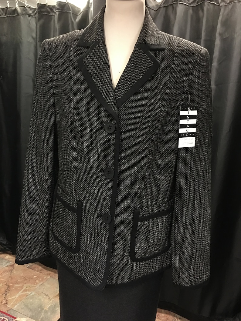 Puede incluir: Blazer negro con un patr&oacute;n de tweed blanco y negro. El blazer tiene un ribete negro alrededor del cuello, los bolsillos y los botones. El blazer est&aacute; en un maniqu&iacute;.