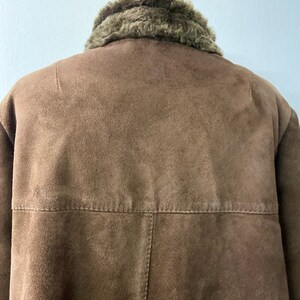 May include: A brown suede jacket with a faux fur collar. The jacket has a zipper closure and two pockets.