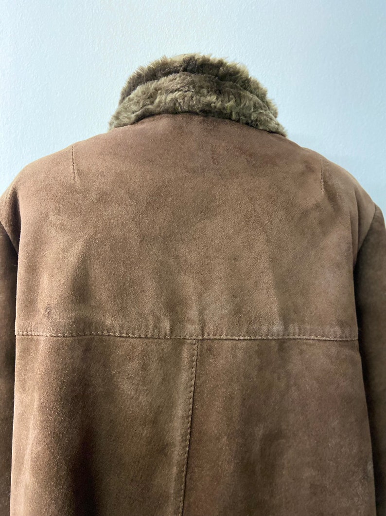 May include: A brown suede jacket with a faux fur collar. The jacket has a zipper closure and two pockets.