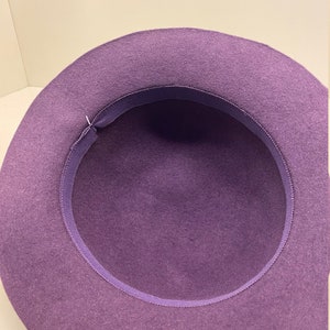 May include: Purple felt fedora hat with a purple ribbon around the inside of the brim.