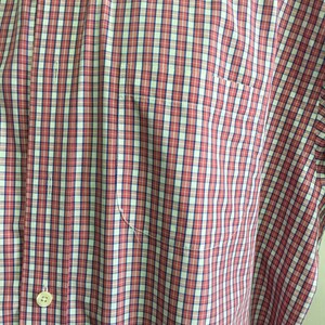 Pu&ograve; includere: Una camicia a bottoni a quadri rossi e bianchi con una chiusura a bottone singolo e una tasca sul lato sinistro.