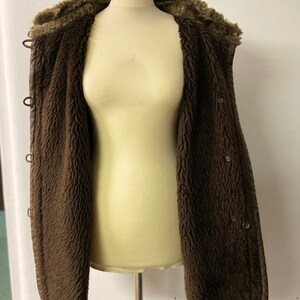 May include: A brown faux fur lined jacket with a snap closure and a hood.