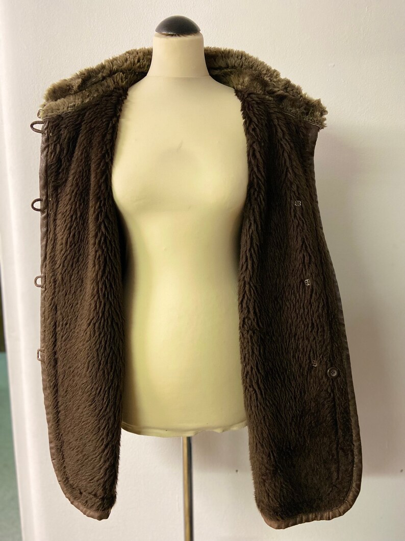 May include: A brown faux fur lined jacket with a snap closure and a hood.
