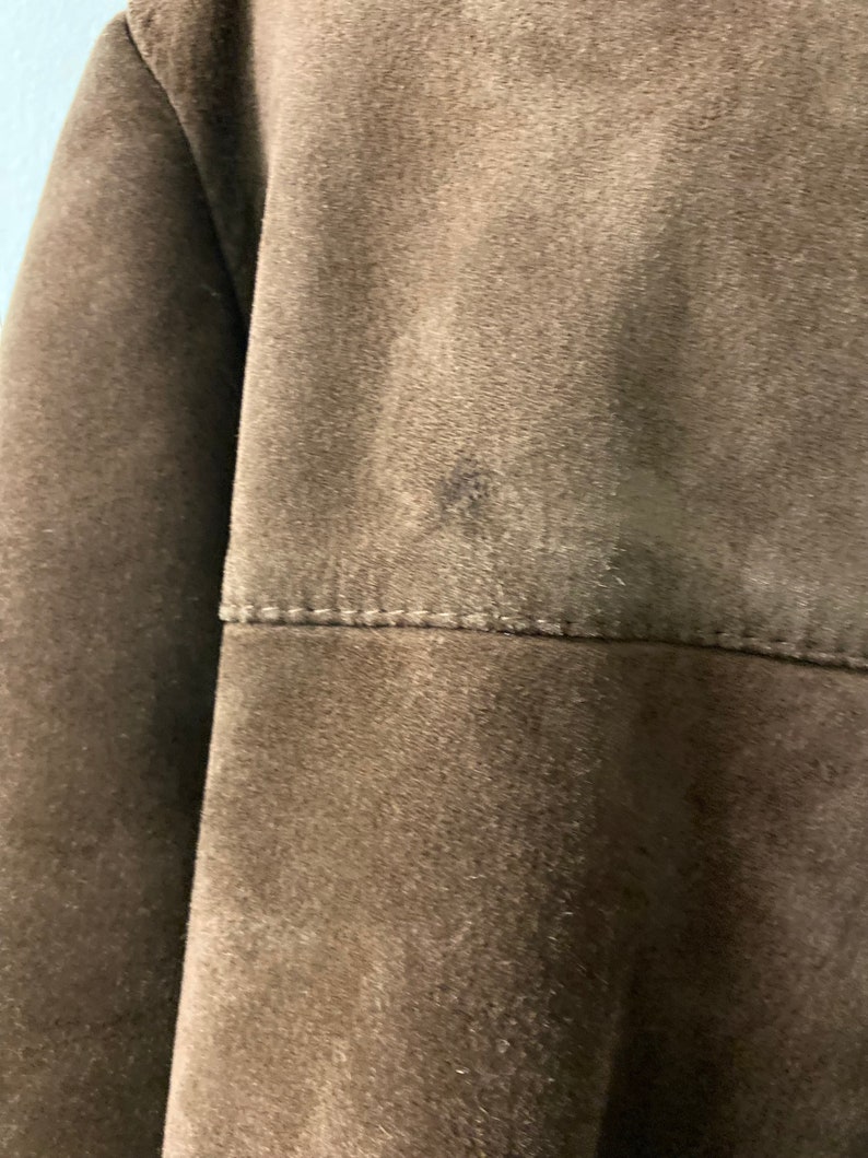 May include: A brown suede jacket with a seam across the back.