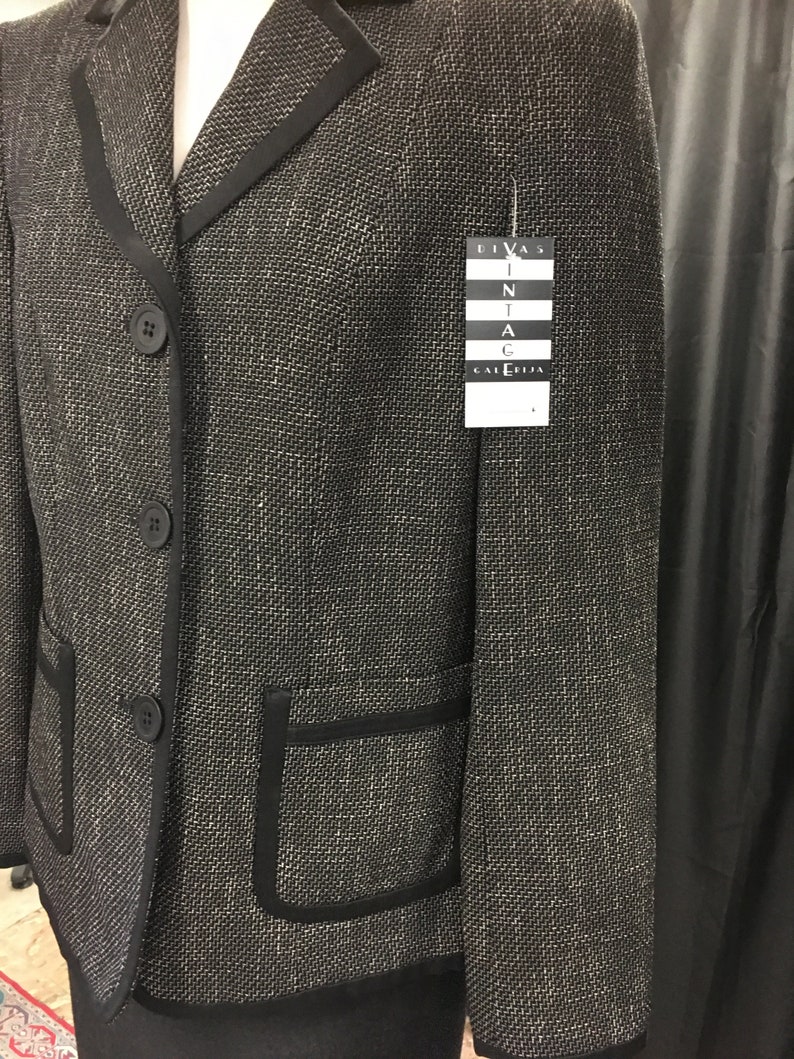 Puede incluir: Blazer de tweed negro y blanco con ribetes negros y un bolsillo en el lado izquierdo. El blazer tiene tres botones y una etiqueta que dice "Divas Vintage Galleria".