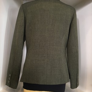 Op de afbeelding: Een groene blazer van een getextureerde stof. De blazer heeft een enkele knoopsluiting en lange mouwen.