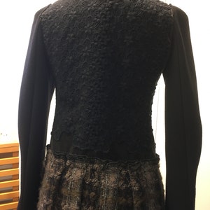 Puede incluir: Chaqueta negra con una superposici&oacute;n de encaje y una falda con estampado marr&oacute;n y negro.