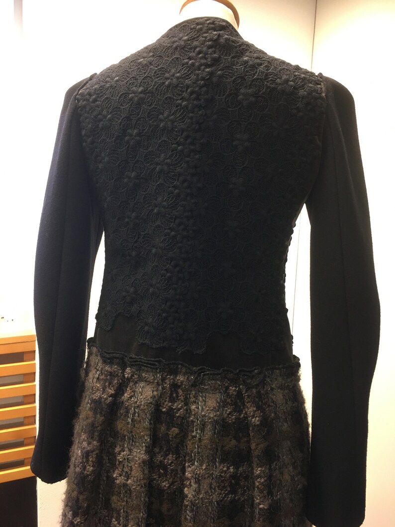 Puede incluir: Chaqueta negra con una superposici&oacute;n de encaje y una falda con estampado marr&oacute;n y negro.