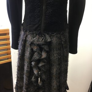 Puede incluir: Vestido negro con un corpi&ntilde;o de encaje negro y una falda de cuadros grises y negros con un detalle de volantes en la parte posterior.