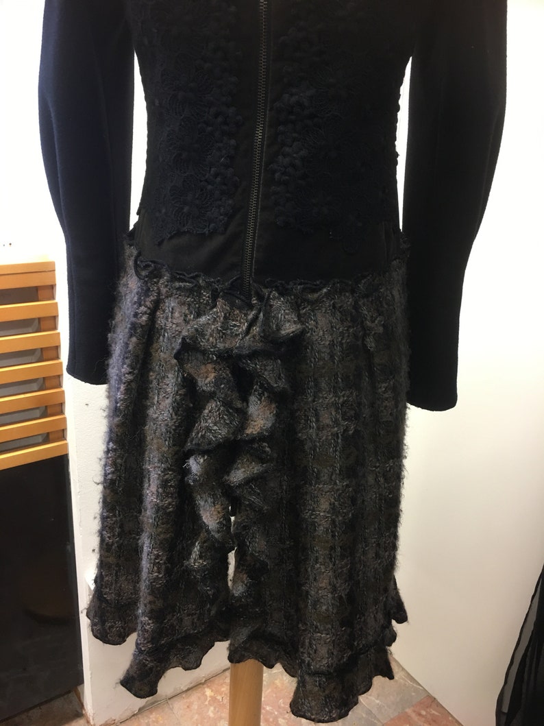 Puede incluir: Vestido negro con un corpi&ntilde;o de encaje negro y una falda de cuadros grises y negros con un detalle de volantes en la parte posterior.