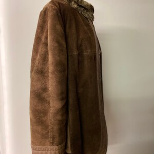 May include: A brown suede jacket with a faux fur collar. The jacket has a zipper closure and a buttoned flap.