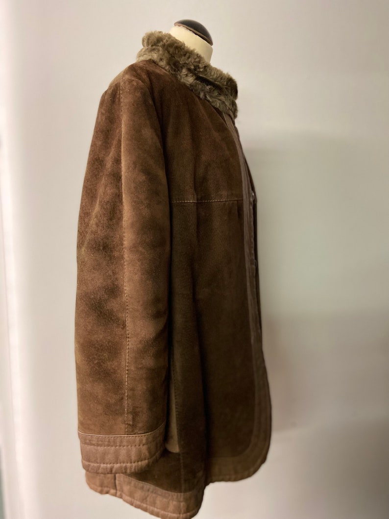 May include: A brown suede jacket with a faux fur collar. The jacket has a zipper closure and a buttoned flap.