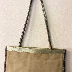May include: A beige canvas tote bag with a gold leather trim and multi-coloured patterned straps.