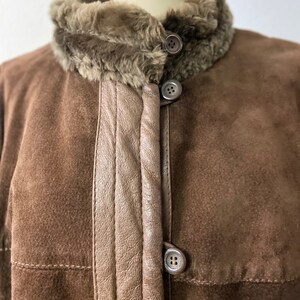 May include: A brown suede jacket with a faux fur collar and three buttons down the front.