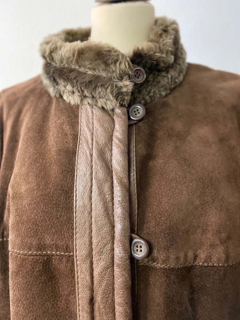 May include: A brown suede jacket with a faux fur collar and three buttons down the front.