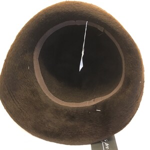 Puede incluir: Sombrero de fieltro marr&oacute;n con ala ancha y forro de sat&eacute;n marr&oacute;n. El sombrero est&aacute; dado la vuelta para mostrar el forro.