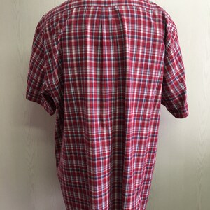 Puede incluir: Camisa de manga corta a cuadros rojos y blancos.