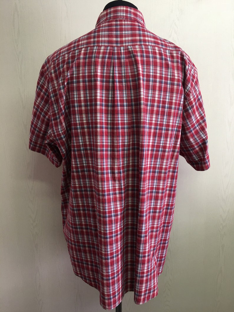 Puede incluir: Camisa de manga corta a cuadros rojos y blancos.
