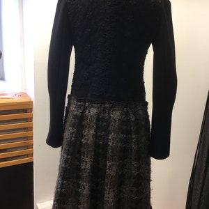 Puede incluir: Vestido negro con una parte superior texturizada, similar a encaje, y una falda de cuadros negros y grises.