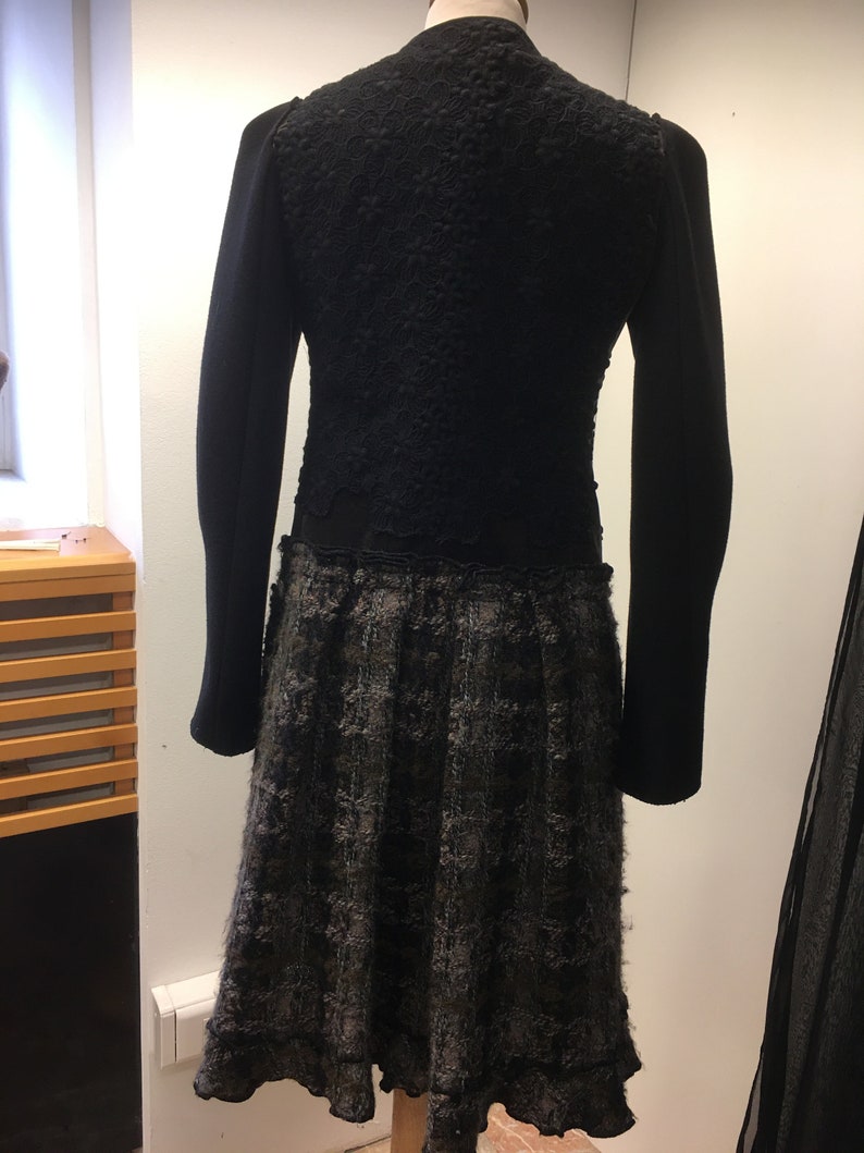 Puede incluir: Vestido negro con una parte superior texturizada, similar a encaje, y una falda de cuadros negros y grises.