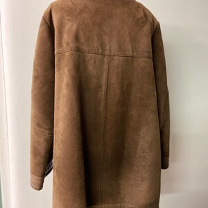 May include: A brown suede jacket with a faux fur collar. The jacket has a long, straight cut and a zipper closure.