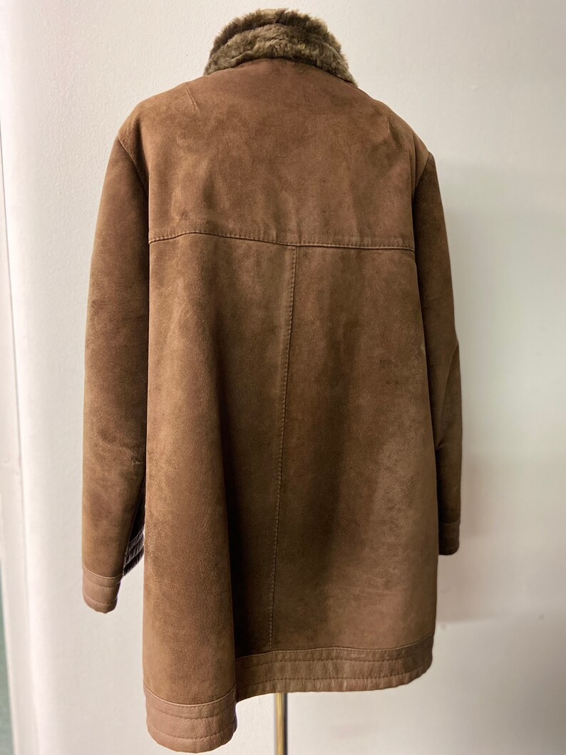May include: A brown suede jacket with a faux fur collar. The jacket has a long, straight cut and a zipper closure.