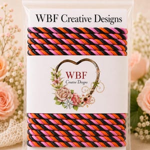 May include: A clear plastic bag containing two sections of twisted rope trim in alternating black, orange, and pink colors. The packaging features a white card with the text WBF Creative Designs and a heart-shaped floral graphic logo.
