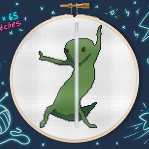May include: A cross-stitch pattern of a green alien dancing on a pole. The pattern is in a white embroidery hoop with a wooden frame. The text "110 x 65 stitches" is written in pink on a blue background.