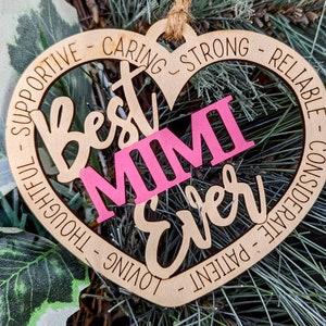 Puede incluir: Adorno de madera en forma de corazón con el texto "Best Mimi Ever" en escritura cursiva. Las palabras "Supportive", "Caring", "Strong", "Reliable", "Considerate", "Patient", "Loving" y "Thoughtful" están escritas alrededor del borde del corazón.