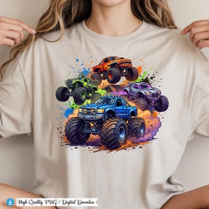 K&ouml;nnte beinhalten: Beiges T-Shirt mit einem farbenfrohen Grafikdesign von f&uuml;nf Monstertrucks. Die Trucks sind in Rot, Gr&uuml;n, Blau und Lila dargestellt, mit &uuml;bergro&szlig;en Reifen und detaillierten Designs. Farbspritzer erzeugen einen dynamischen Effekt.