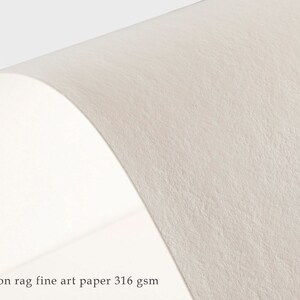 May include: Close-up of a textured, off-white fine art paper. The paper is 100% cotton rag and weighs 316 gsm.