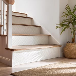 May include: Wooden staircase with white risers featuring a geometric pattern. The steps have a natural wood finish. A woven basket with a green plant sits nearby. The stairs are part of a home decor theme.