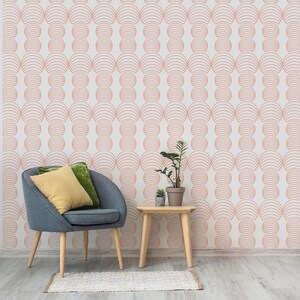 May include: A living room with a light pink and white patterned wallpaper. A gray armchair with a yellow pillow and a green pillow sits in front of a small wooden table with a potted plant on top.