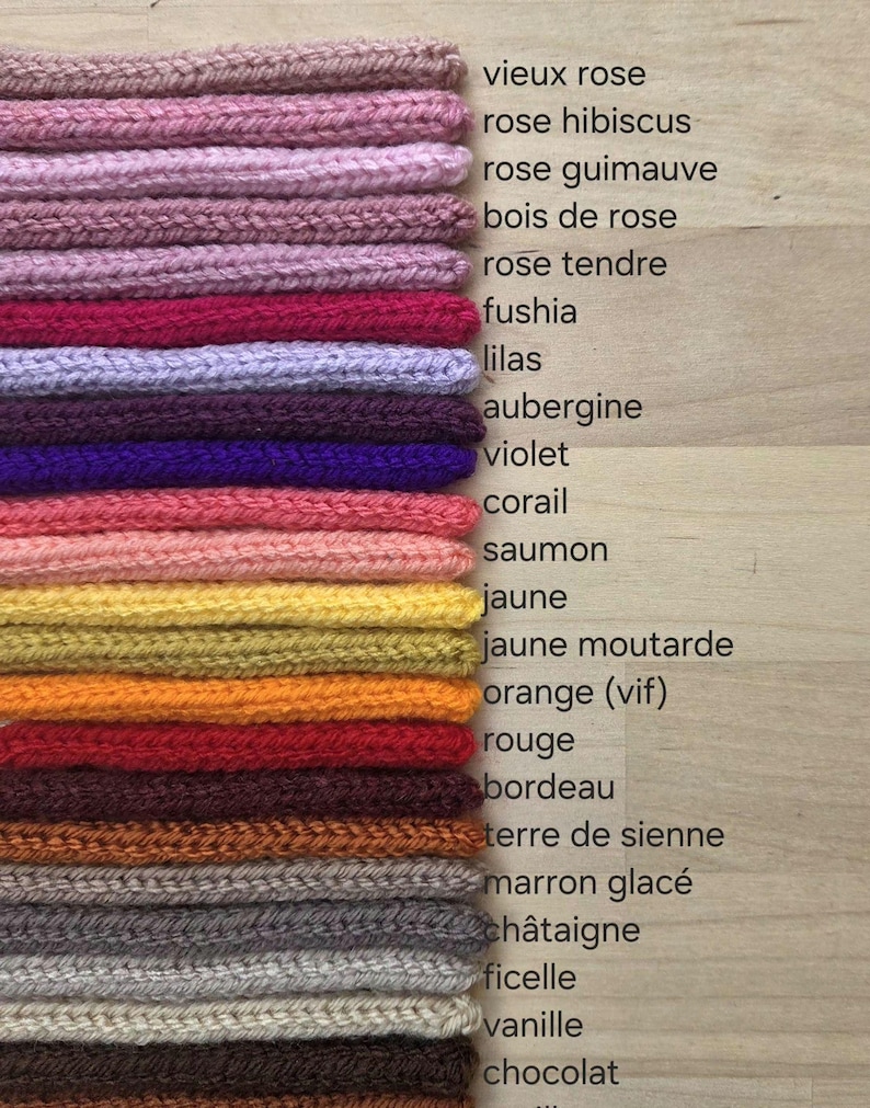 May include: A stack of twenty-one knitted fabric swatches in various colors, each labeled with French text including vieux rose, rose hibiscus, rose guimauve, bois de rose, rose tendre, fushia, lilas, aubergine, violet, corail, saumon, jaune, jaune moutarde, orange, rouge, bordeau, terre de sienne, marron glac&eacute;, ch&acirc;taigne, ficelle, vanille, and chocolat.