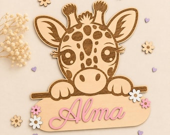 May include: Wooden giraffe wall decoration featuring the name "Alma" in pink script. The giraffe has brown spots and is surrounded by wooden flowers and heart shapes. The design is light and airy, suitable for a nursery.